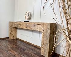 a wooden table sitting on top of a hard wood floor next to a tall plant