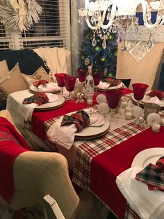 a dining room table set for christmas with red and white plaid napkins on it