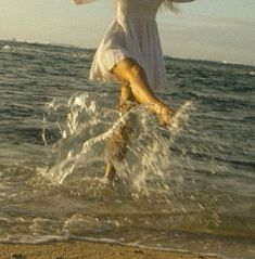 a woman is jumping into the water at the beach