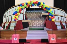 the stage is set up for an event with balloons on it and boxes under them