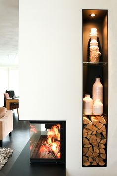 a fireplace with logs in it next to a wall mounted fire place and vases