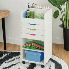 a white desk with drawers on it and a potted plant in the corner next to it