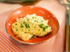 a small orange bowl filled with mashed potatoes and garnished with parsley