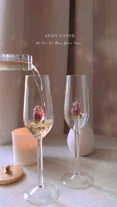 two wine glasses sitting on top of a table next to a candle holder and vase