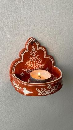 a candle holder with a flower design on the side and a lit candle in it