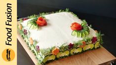 a square cake with cucumbers and flowers on it sitting on a cutting board