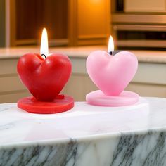 two heart shaped candles sitting on top of a marble table