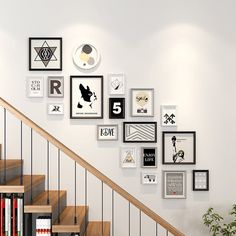 there are many framed pictures on the wall next to the stair case and bookshelf