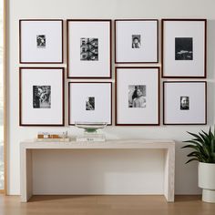 a white table topped with pictures next to a potted plant