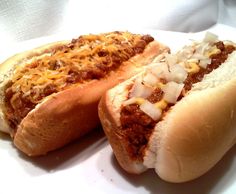 two chili dogs with cheese and onions on them