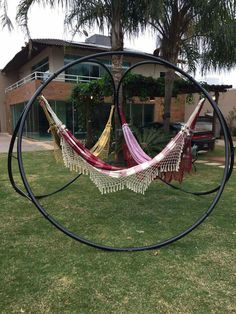 two hammocks are in the middle of a circle on grass near a building