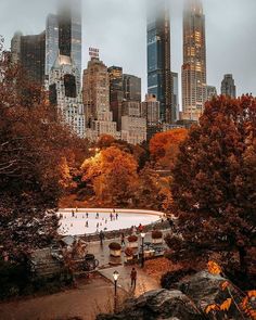 people skating on an ice rink in front of the city's tall skyscrapers