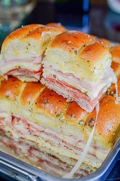 several ham and cheese sandwiches stacked on top of each other in a plastic container,