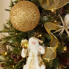 a christmas tree decorated with gold and white ornaments, including a santa clause ornament