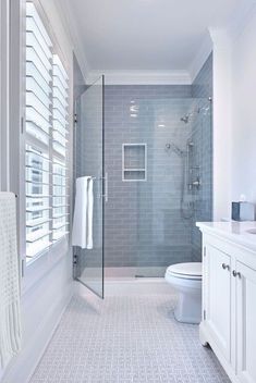 a bathroom with a toilet, sink and shower in it's stall area next to a window