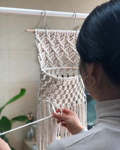 a woman is weaving a wall hanging