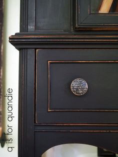 a close up of a black cabinet with a metal knob on the door and bottom drawer