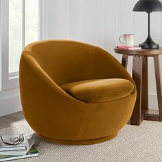 a yellow chair sitting on top of a rug next to a table with a lamp