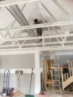 a man on a ladder working on the ceiling in a room under construction with unfinished walls