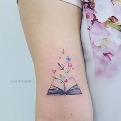 an open book tattoo on the left side of the leg, with hearts coming out of it