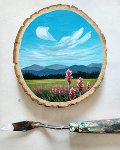 a painting on a piece of wood with paintbrush next to it