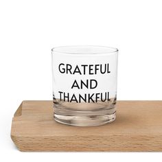 a shot glass with the words grateful and thank on it sitting on a wooden coaster