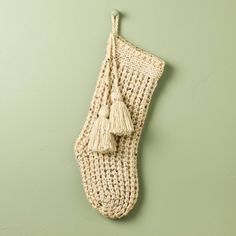 a knitted stocking hanging on a green wall with tassels in it