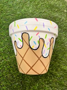 a paper cup with sprinkles and ice cream on it sitting in the grass