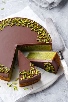 there is a chocolate cake with pistachios on the top and one slice missing