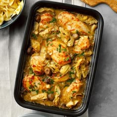 a casserole dish with chicken, artichokes and pasta on the side