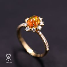 an orange and white diamond ring on a black surface