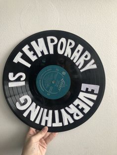 someone holding up a record with the words temporary on it in front of a white wall