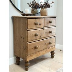 a wooden dresser sitting in front of a mirror on top of a hard wood floor