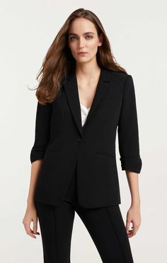 a woman is wearing a black suit and pants