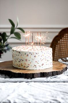 a cake with white frosting and sprinkles sitting on top of a wooden board