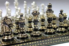 the chess board is made out of metal and has black and gold pieces on it