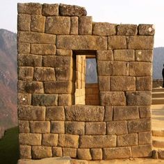 a man standing on top of a stone wall next to a window in the side of a building