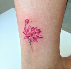 a woman's leg with a pink flower tattoo on her left side ribcage