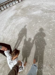 two people standing in the snow with their shadows cast on them and one person holding his hand