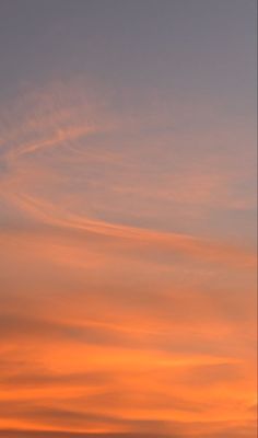 an airplane is flying in the sky at sunset