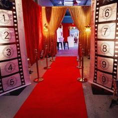 a red carpeted hallway leading to an open door with numbers on it and two large doors at the end