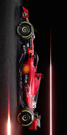 a red race car driving down a track with its lights on and the front wheel spinning