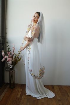 a woman in a white wedding dress with flowers on her head and veil over her face