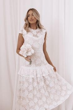 a woman in a white dress holding flowers