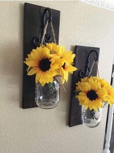 two mason jars with sunflowers are hanging on the wall next to each other