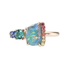 Vibrant sapphires and a vivid emerald shine spiritedly in this Australian Opal Ring. Chromatically coordinated with the Boulder Opal, the ombré palette is embraced in rose gold. Minty green radiates outward as though luminescing from within the opal and emerald ring. Down the periphery of the opal flows a sequence of rainbow sapphires, ascribing to the colors inside the stone. Bookended by a bright blue sapphire, the chromatic palette of the unique ring is potently punctuated, embracing its guided destiny. A rare piece of jewelry art, this opal ring began with a different center stone that broke during setting. After an exacting search for a new stone, recutting work and reshaping of the mounting, a new piece took form. Crafted in 14k rose gold with pave and prong setting, this blue opal r Blue Opal Jewelry, Boulder Opal Ring, Australian Opal Ring, Blue Opal Ring, Rainbow Sapphires, Minty Green, Australian Boulder Opal, Opal Earrings Stud, Opal Studs