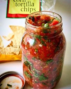 a jar filled with lots of food next to a small bowl of dipping sauces