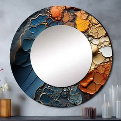 a round mirror sitting on top of a table next to vases and flowers in front of a gray wall