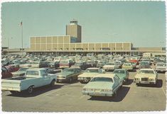 a parking lot full of cars in front of a large building with a clock tower