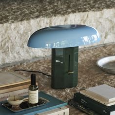 a lamp sitting on top of a table next to books and a bottle of wine